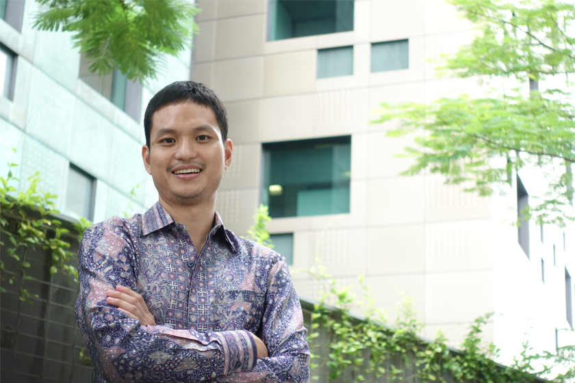 A smiling man wearing batik shirt crossing arms